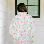 Woman with dark hair wearing a top in the Tori body style featuring pink & green nutcracker graphics. Model paired this top with faux leather leggings.