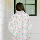 Woman with dark hair wearing a top in the Tori body style featuring pink & green nutcracker graphics. Model paired this top with faux leather leggings.